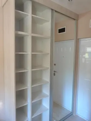 a walk in closet with white shelves and a door at Apartments Sia in Kopaonik