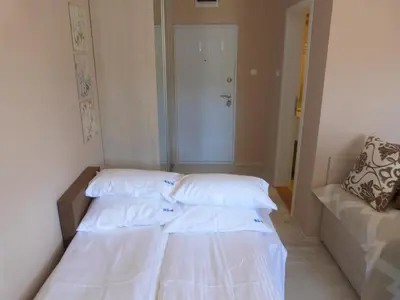 two beds in a small room with a couch at Apartments Sia in Kopaonik