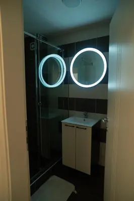 a bathroom with a shower and a sink and two mirrors at Nedodjija apartman in Leskovac