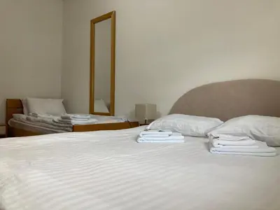 a bedroom with two beds with white sheets and a mirror at Vila Nina Kopaonik in Kopaonik