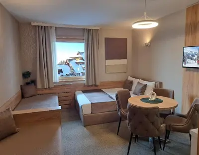a living room with a couch and a bed and a table at Celestis Apartmani Konaci in Kopaonik