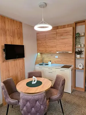 a kitchen with a table and chairs and a sink at Celestis Apartmani Konaci in Kopaonik