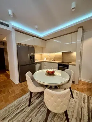 a kitchen with a white table and chairs in a room at Comfortable Nis Apartment in Niš