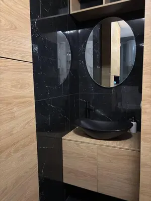 a black bathroom with a sink and a mirror at Comfortable Nis Apartment in Niš