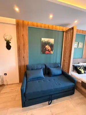a living room with a blue couch and a bed at Mountain Nest - Milmari Resort & Spa in Kopaonik