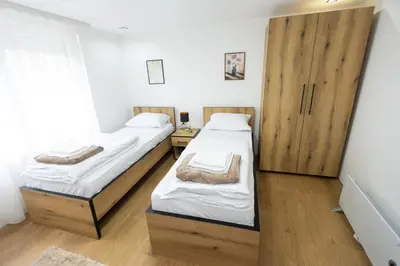 two beds in a room with wooden cabinets at Bakina kuca in Pirot