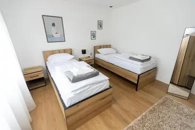 two beds in a room with white walls and wooden floors at Bakina kuca in Pirot