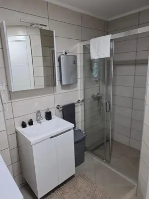 a bathroom with a white sink and a shower at POSEJDON DELUXe 4 in Vrnjačka Banja