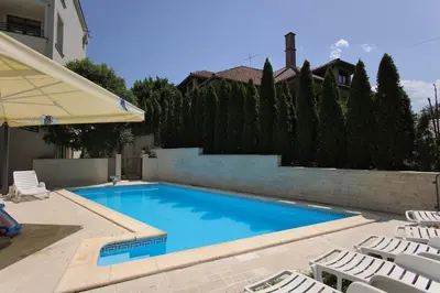 a swimming pool with white chairs and a house at Apartman A4 - Vila Opera in Vrnjačka Banja