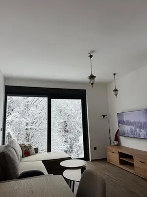 a living room with a couch and a large window at Rajski Kutak Kopaonik in Kopaonik
