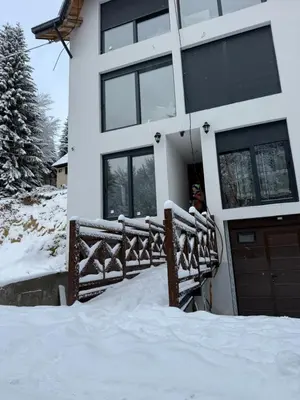 a house covered in snow with a wooden fence at Rajski Kutak Kopaonik in Kopaonik