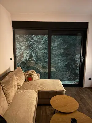 a living room with a couch and a large window at Rajski Kutak Kopaonik in Kopaonik