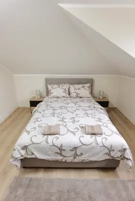 a white bedroom with a bed with two pillows at Apartman Danica in Vrnjačka Banja