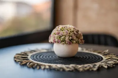 a white vase with flowers sitting on a table at Ryo Golden Imperial 2 in Kruševac
