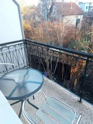 a glass table and two chairs on a balcony at Apartman Javor in Vrnjačka Banja
