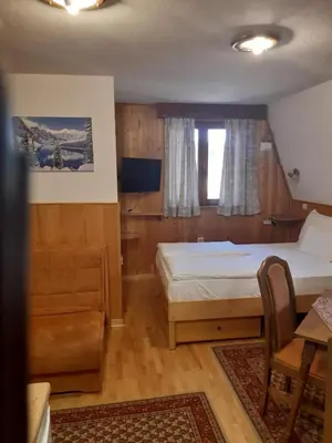 a bedroom with two beds and a desk and a table at Vila Paraglajder in Kopaonik