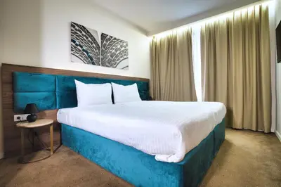 a bedroom with a large bed with a blue headboard at Hotel Nais Nis Autoput in Niš