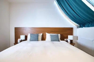 a bedroom with a large white bed with a wooden headboard at Hotel Nais Nis Autoput in Niš