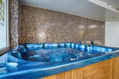 a blue tub in a bathroom with a tiled wall at Hotel Nais Nis Autoput in Niš