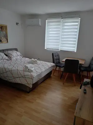 a bedroom with a bed and a table and chairs at LIN Apartman in Vladičin Han