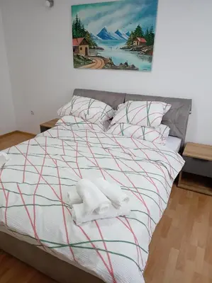 a bed with white blankets and pillows on it at LIN Apartman in Vladičin Han