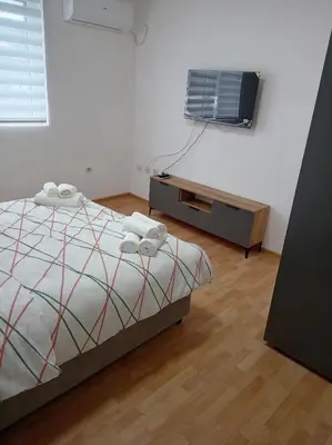 a bedroom with a bed and a tv on a wall at LIN Apartman in Vladičin Han