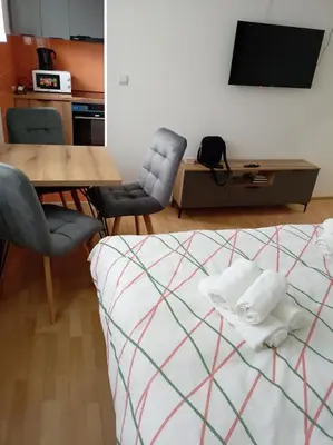 a bedroom with a bed and a table and chairs at LIN Apartman in Vladičin Han
