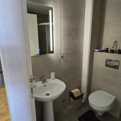 a bathroom with a sink and a toilet and a mirror at Apartman IVA LUX Vrnjacka Banja in Vrnjci