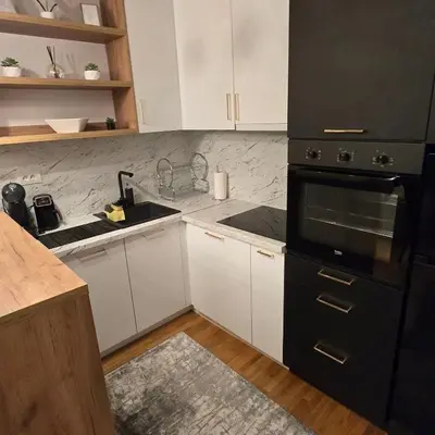 a kitchen with a black refrigerator and white cabinets at Apartman IVA LUX Vrnjacka Banja in Vrnjci