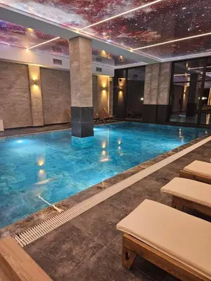 a swimming pool with blue water in a building at Sierra Apartments Residence Hill & SPA Centar in Kopaonik