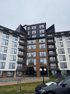 a large apartment building with a car parked in front at Sierra Apartments Residence Hill & SPA Centar in Kopaonik