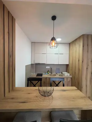 a kitchen with a wooden table and a light at Apartman Pogled Contra in Kopaonik