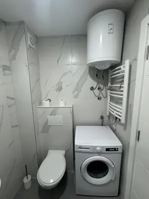 a small bathroom with a toilet and a washing machine at Apartman Pogled Contra in Kopaonik