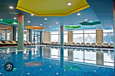 a swimming pool in a building with chairs at Kraljevi Čardaci - Despot Apartman in Kopaonik