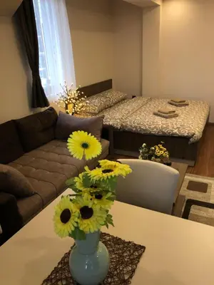 a living room with a vase with yellow flowers on a table at Apartmani Glamur Kopaonik in Kopaonik