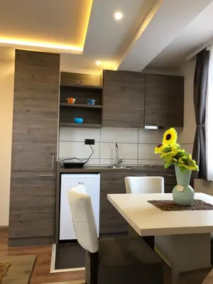 a kitchen with wooden cabinets and a white table at Apartmani Glamur Kopaonik in Kopaonik