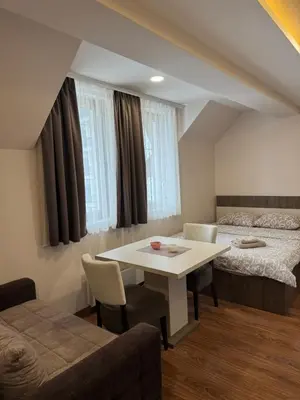 a room with a bed and a white table and chairs at Apartmani Glamur Kopaonik in Kopaonik