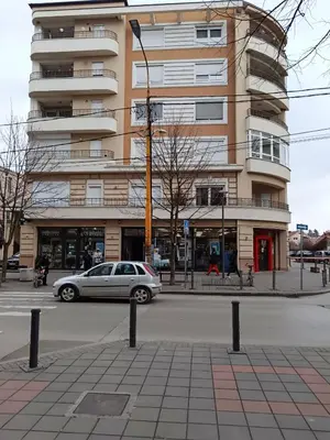 a car parked in front of a tall building at Apartman Vuk in Ćuprija