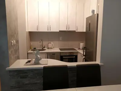 a kitchen with white cabinets and a table and a refrigerator at Apartman Vuk in Ćuprija