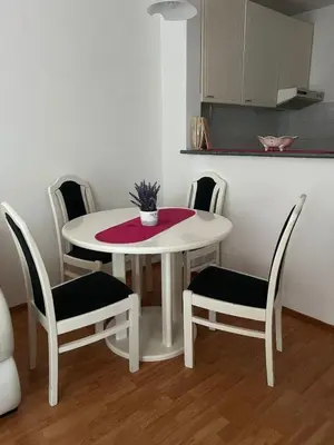a white table and chairs with a table and a kitchen at Apartmani Vrnjacka Banja 7 in Vrnjačka Banja