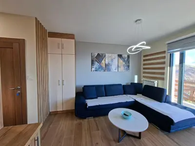 a living room with a blue couch and a table at Nebeska Treska in Kopaonik