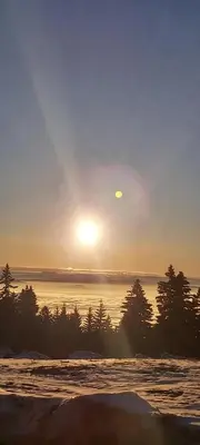 a sunset over the water with trees in the foreground at Nebeska Treska in Kopaonik