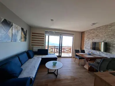 a living room with a blue couch and a table at Nebeska Treska in Kopaonik