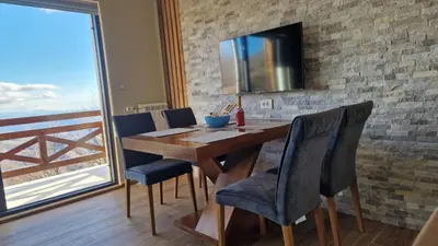 a dining room table with chairs and a television on a brick wall at Nebeska Treska in Kopaonik