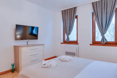 a bedroom with a bed and a tv and windows at Apartmani Central 2 & Free Parking in Vrnjačka Banja