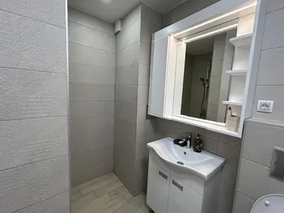 a white bathroom with a sink and a mirror at Apartman Petruska Park in Paraćin