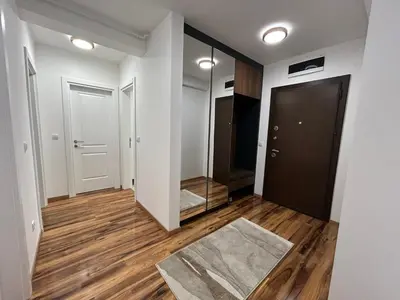 a hallway with white walls and wooden floors and a mirror at Apartman Petruska Park in Paraćin