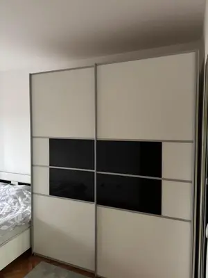 a wardrobe with glass doors in a bedroom at bozicapartments in Jagodina