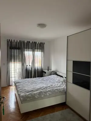 a white bedroom with a bed and a window at bozicapartments in Jagodina