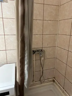 a shower in a tiled bathroom with a shower curtain at Stan in Niš
